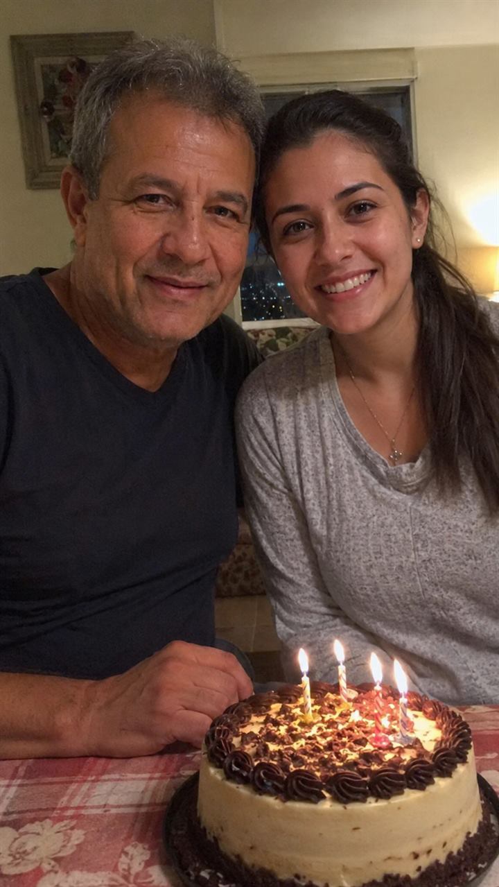A father and daughter smiling beside a birthday cake