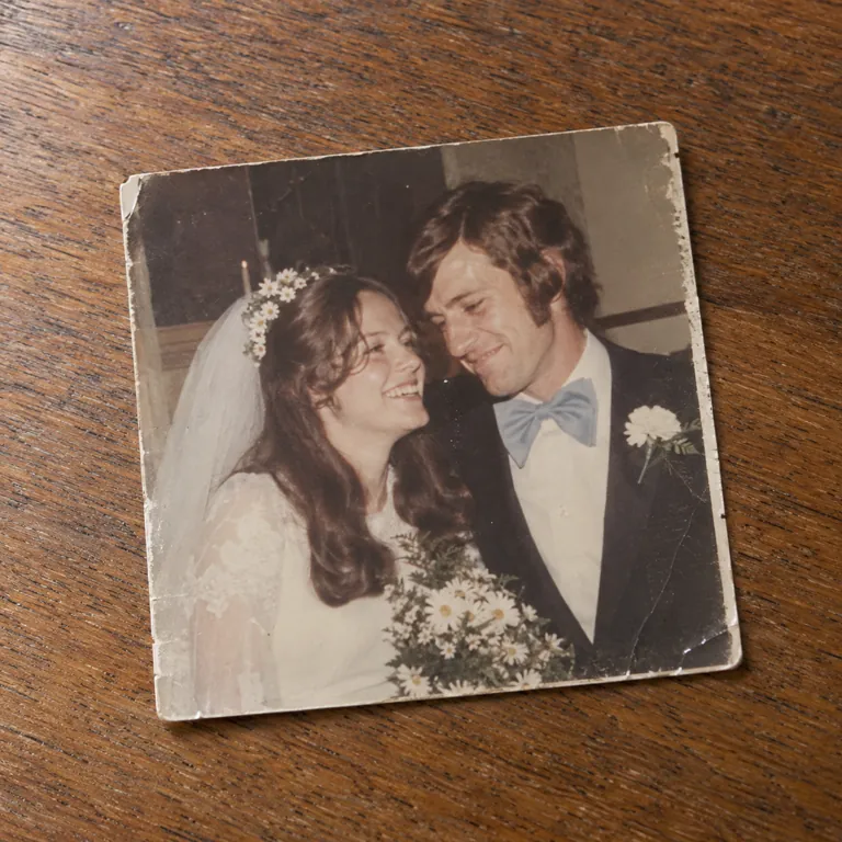 A faded wedding photograph of a laughing bride and a groom in a blue bow tie