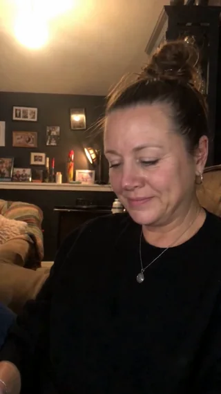 A woman smiles as she listens at home in the evening, a real customer reaction